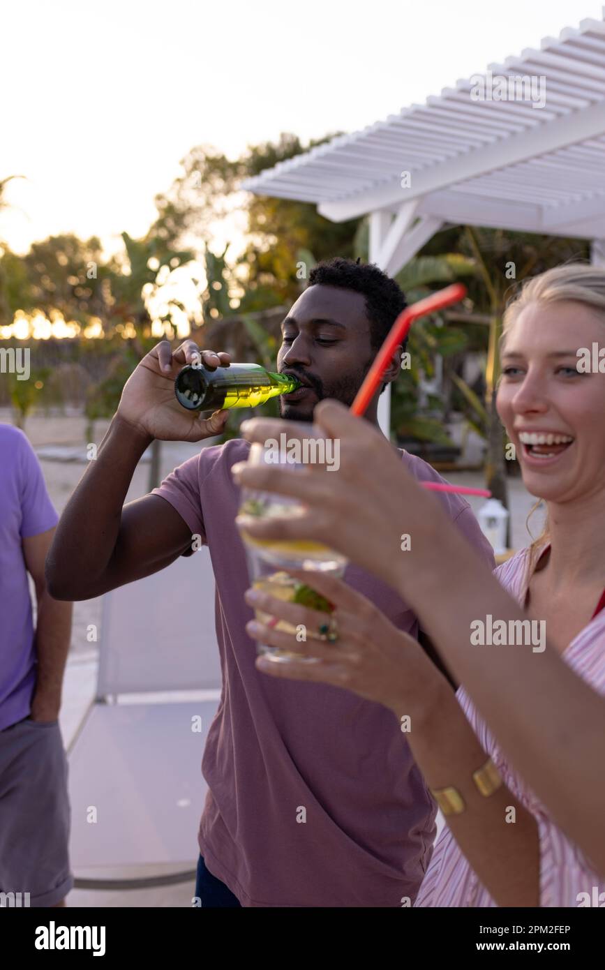 Fröhliche, vielfältige Freunde, die eine Party am Pool feiern, Cocktails und Bier trinken Stockfoto