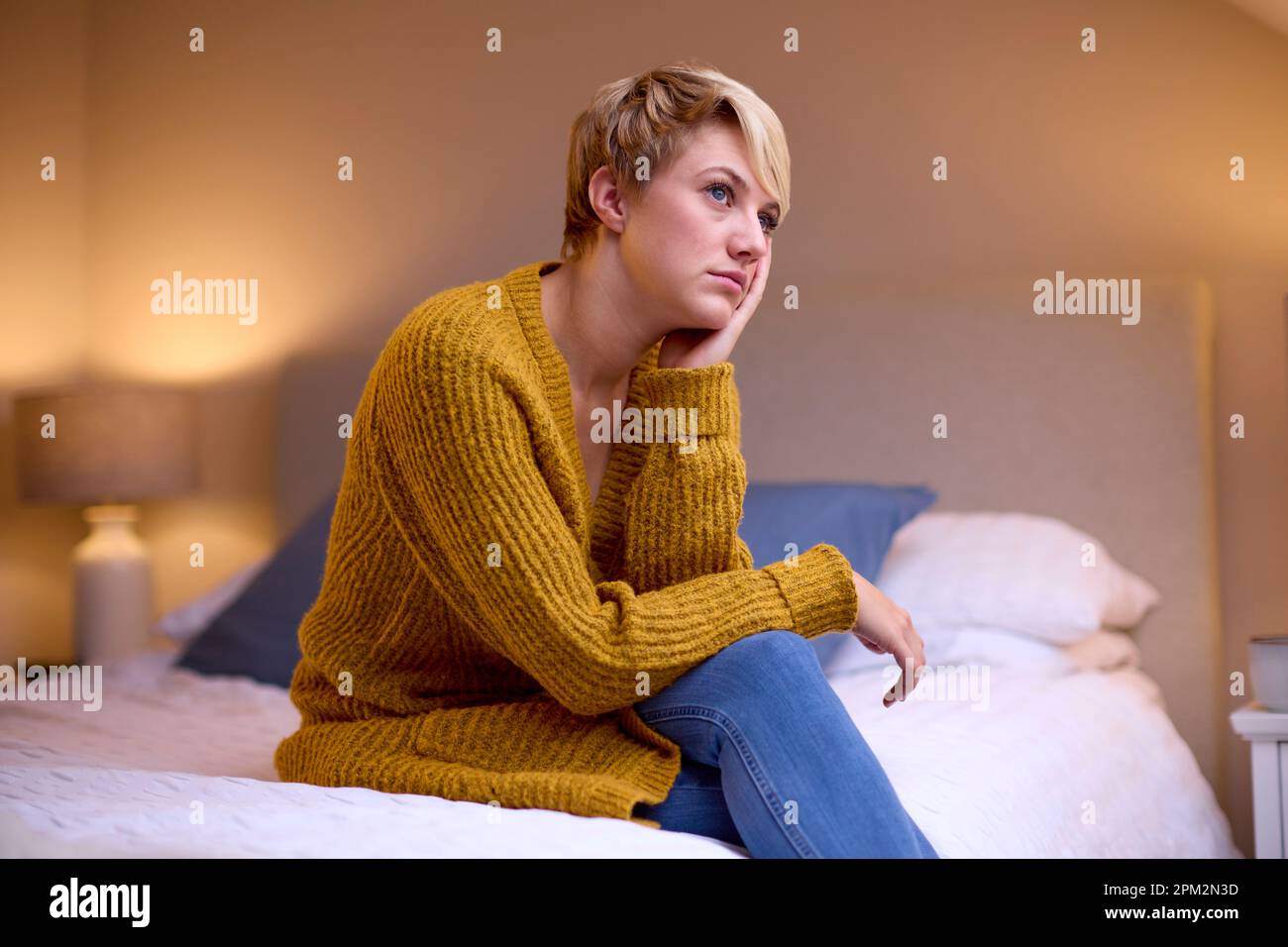 Unglückliche Junge Frau, Die Abends Zu Hause Im Bett Sitzt Stockfoto