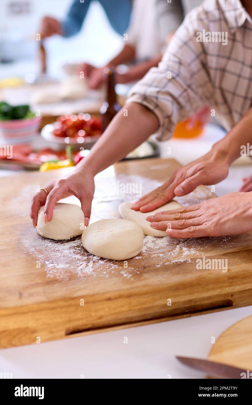 Nahaufnahme Der Gruppe Von Freunden Zu Hause In Der Küche Mit Der Zubereitung Von Pizzas Für Eine Party Zusammen Stockfoto