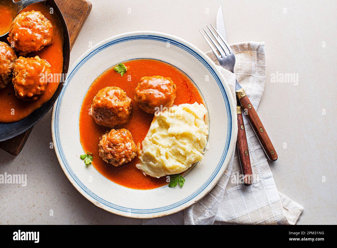 Gebratene Fleischbällchen, geschmort in Tomatensauce, serviert mit Kartoffelpüree auf einem weißen Tisch. Ich esse mit Rind gebratene Fleischbällchen in Tomatensoße. Stockfoto