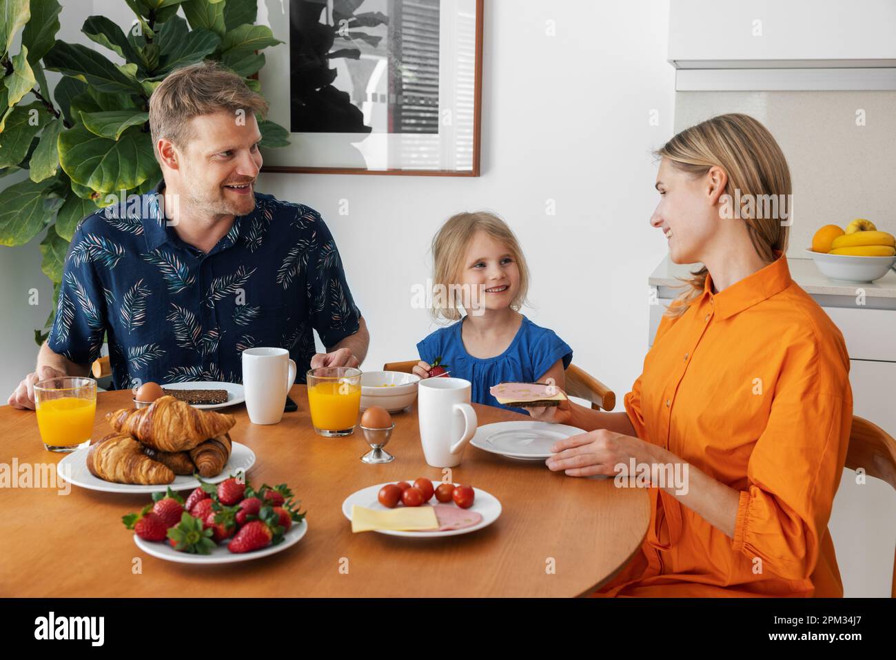 Familienfrühstück. Eltern und Kinder essen morgens am Tisch in der Küche Stockfoto