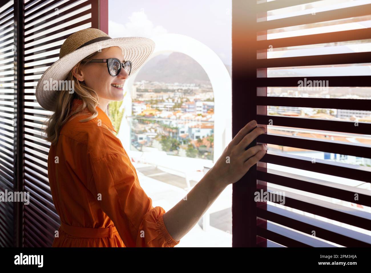 Eine Frau, die auf der Dachterrasse des Penthouse steht, schließt Türen und genießt den Blick über die Stadt Stockfoto