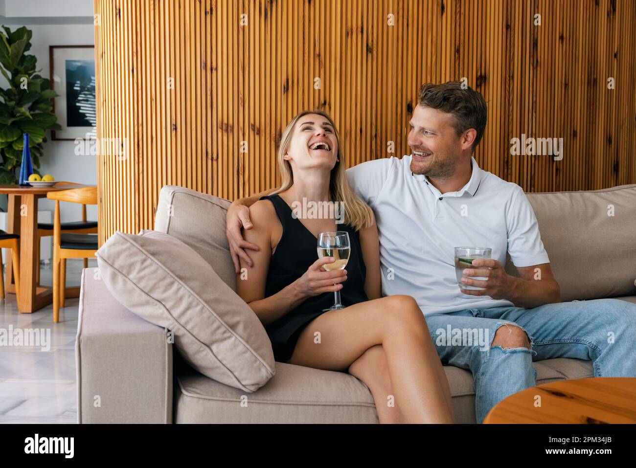 Ein junges Paar geht aus. Mann und Frau sitzen auf der Couch und flirten, während sie Cocktails trinken Stockfoto