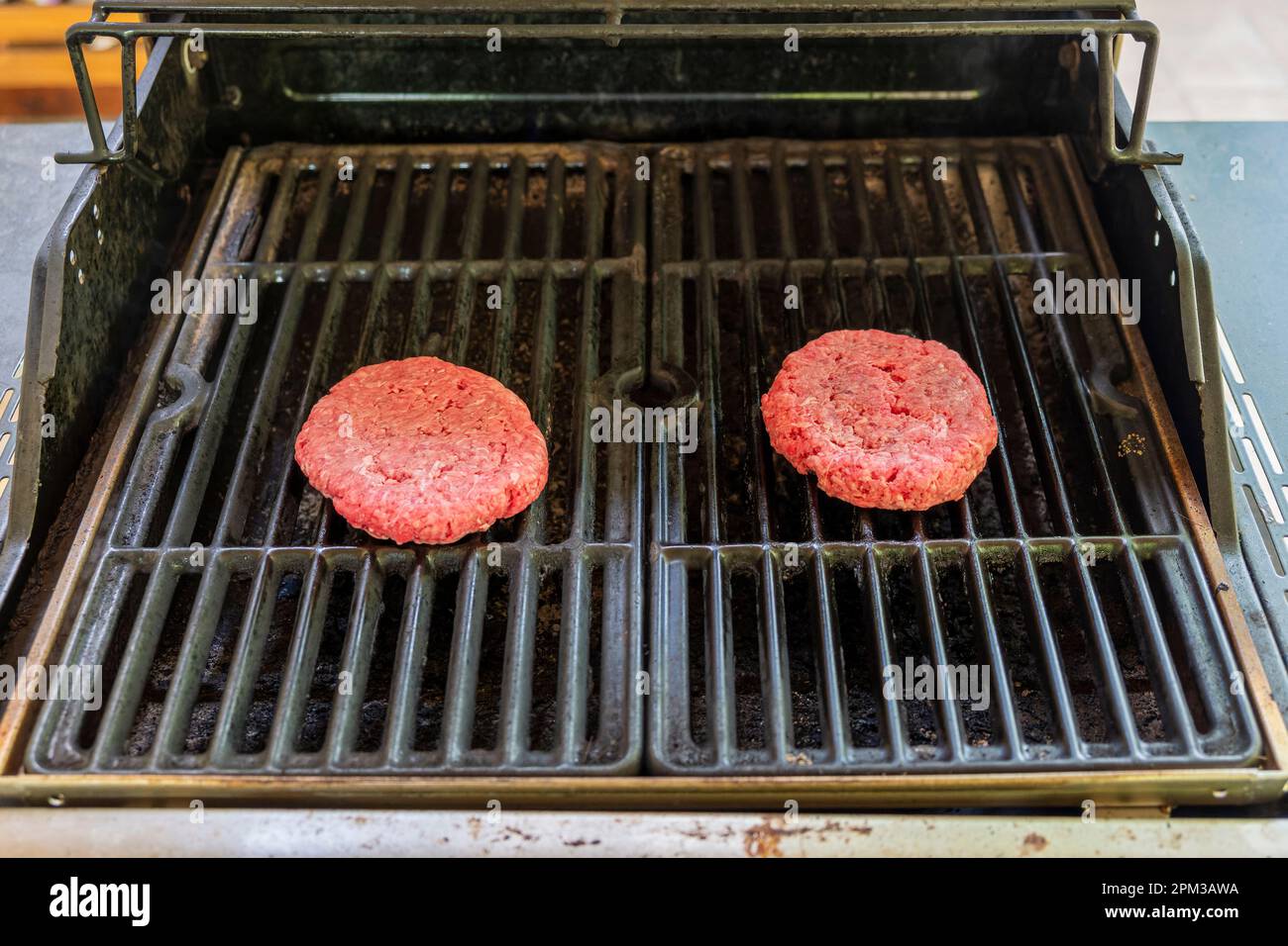 Frische, rohe Hamburger auf einem Gasgrill im Freien in Montgomery, Alabama, USA. Stockfoto