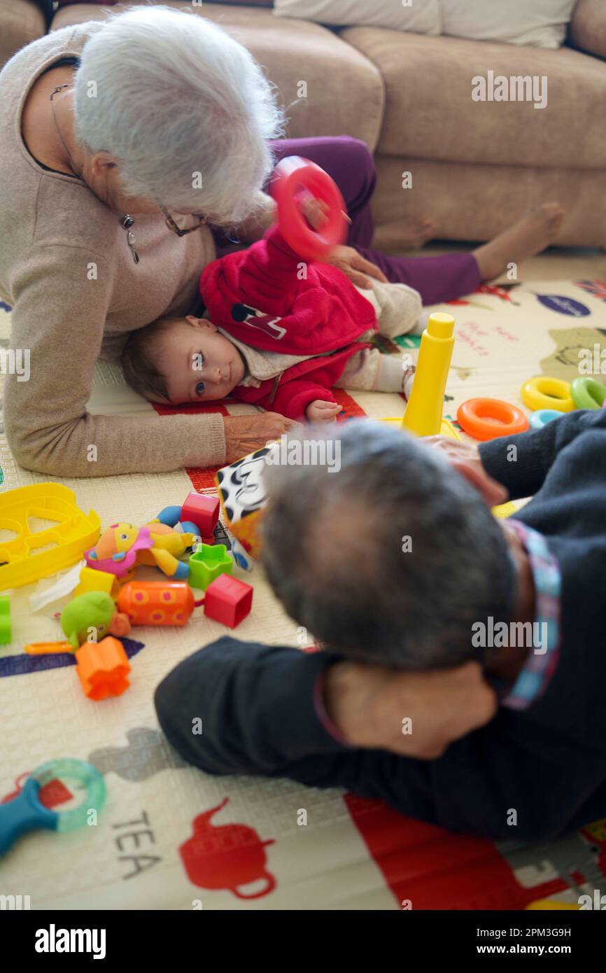 Baby spielt mit seinen Großeltern zu Hause auf dem Boden Stockfoto
