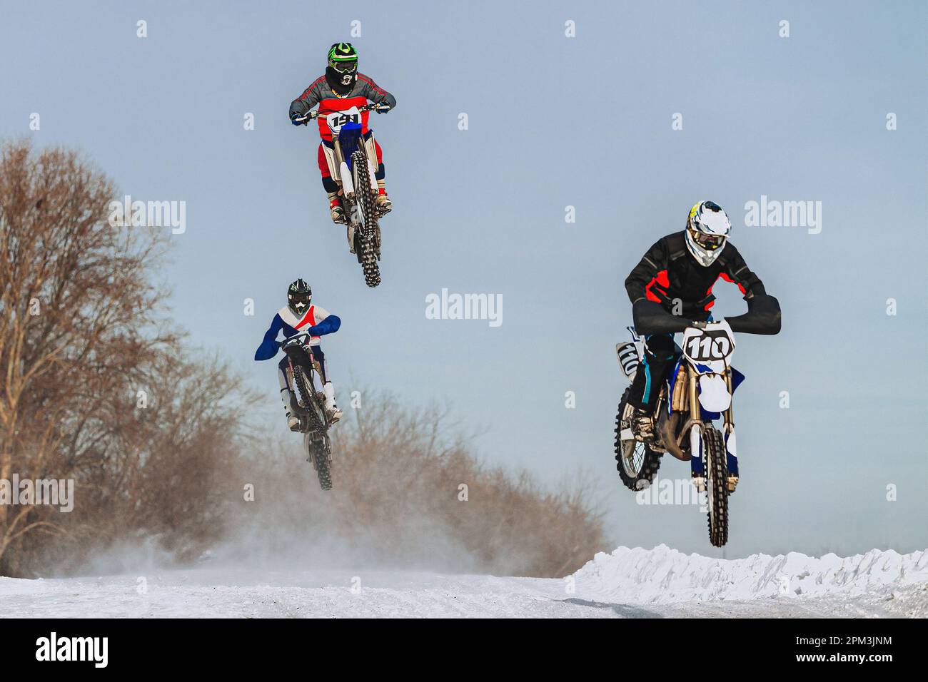 Motocross-Fahrer, der auf einem verschneiten Sprungbrett springt, im Winter Off-Road-Motorradrennen Stockfoto