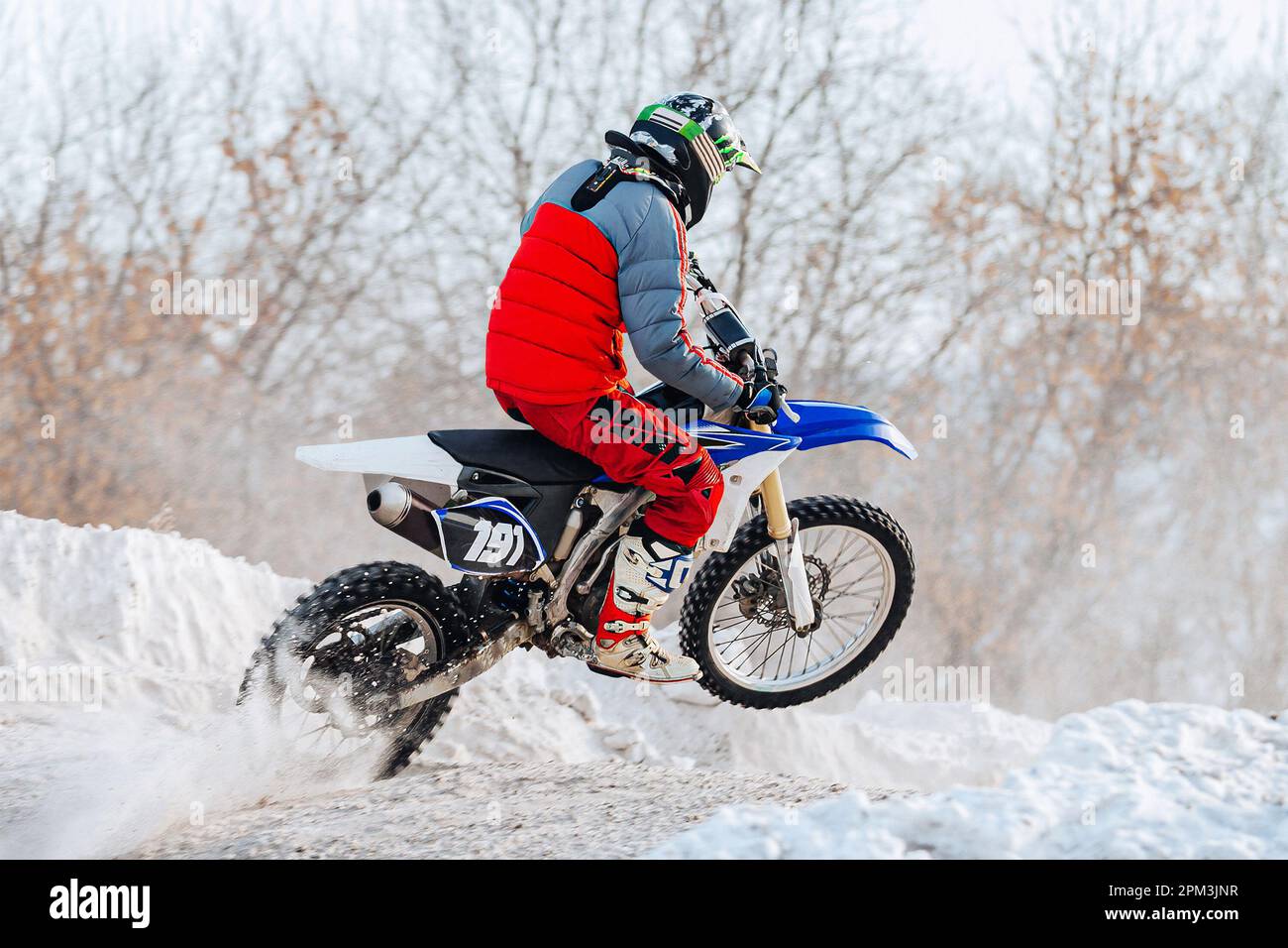 motocross-Fahrer fahren winterliche Off-Road-Motorradrennen, Schnee spritzt unter dem Hinterrad Stockfoto