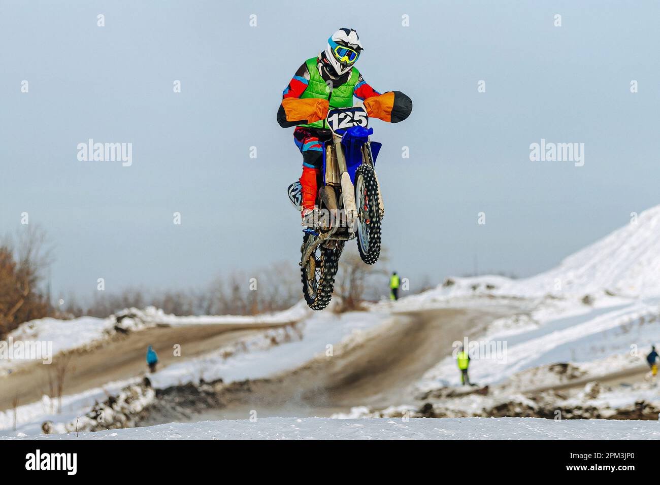 motocross-Fahrer, der auf einem verschneiten Sprungbrett springt, winterliche Off-Road-Motorradrennen Stockfoto