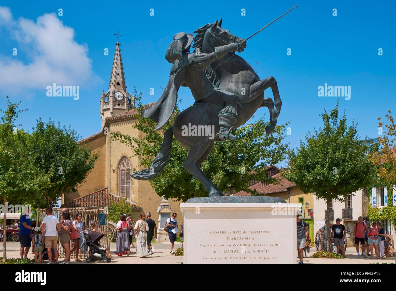 Frankreich, Gers, Lupiac, d'Artagnan Festival, Place d'Artagnan, Erste Reiterstatue des berühmten Musketiers, eingeweiht am 9. August 2015, geformt von Daphne du Barry und der Kirche Saint Barthelemy Stockfoto