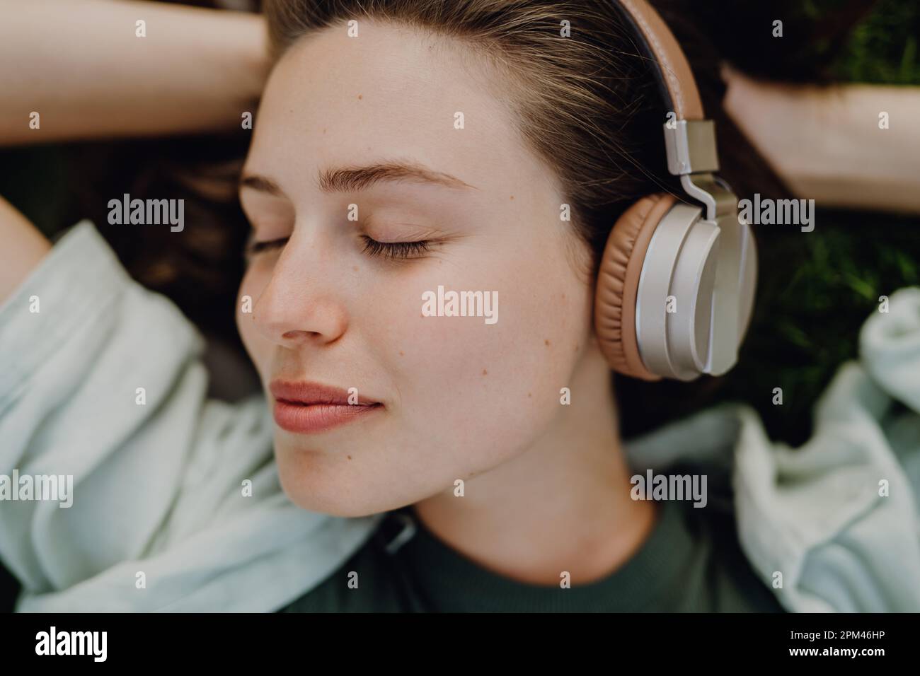 Porträt einer jungen Frau, die über Kopfhörer Musik hört. Stockfoto