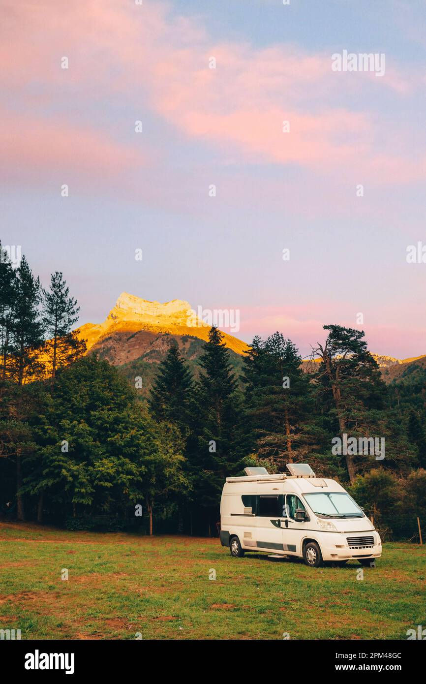 Wohnmobil in einem Camping mit herrlicher Aussicht auf den Wald und die Berge bei Sonnenuntergang. Roadtrip im Minibus und Sommerabenteuer im Freien. Nomad Stockfoto