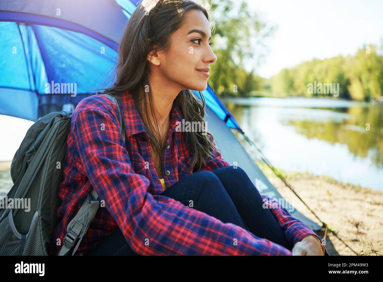 Sie entkommt allem. Eine attraktive junge Frau, die auf ihrem Campingplatz sitzt. Stockfoto