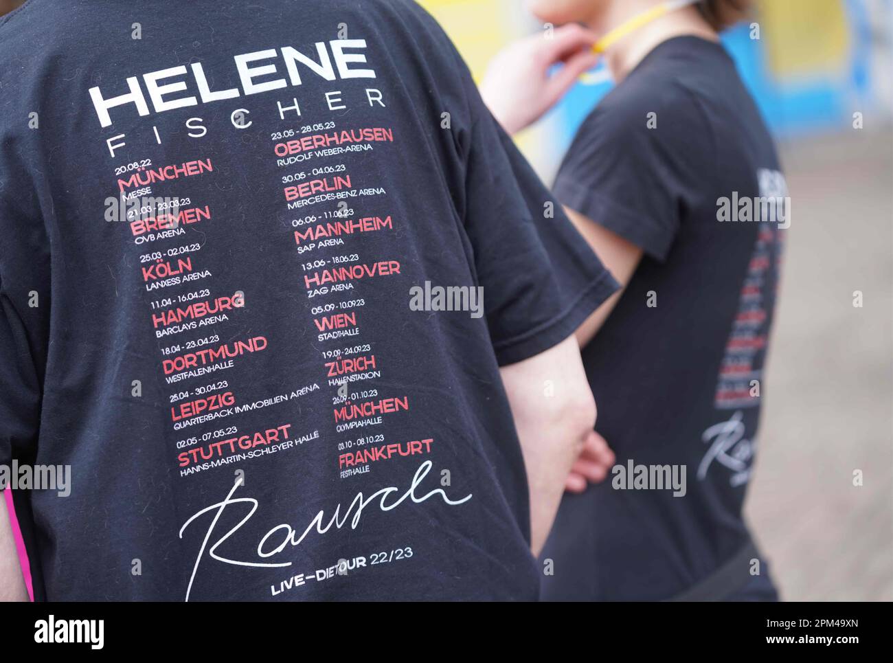 Hamburg, Deutschland. 11. April 2023. Die Fans von Helene Fischer stehen vor der Barclays Arena mit Helene Fischer T-Shirts, auf denen die Tourdaten aller Konzerte auf der Rückseite zu lesen sind. Die Sängerin Helene Fischer beginnt ihre Tour mit dem ersten von fünf Hamburger Konzerten heute Abend. Der Sänger musste den Beginn der Tour in Bremen und das Konzert in Köln aufgrund einer Rippenfraktur verschieben. Kredit: Marcus Brandt/dpa/Alamy Live News Stockfoto