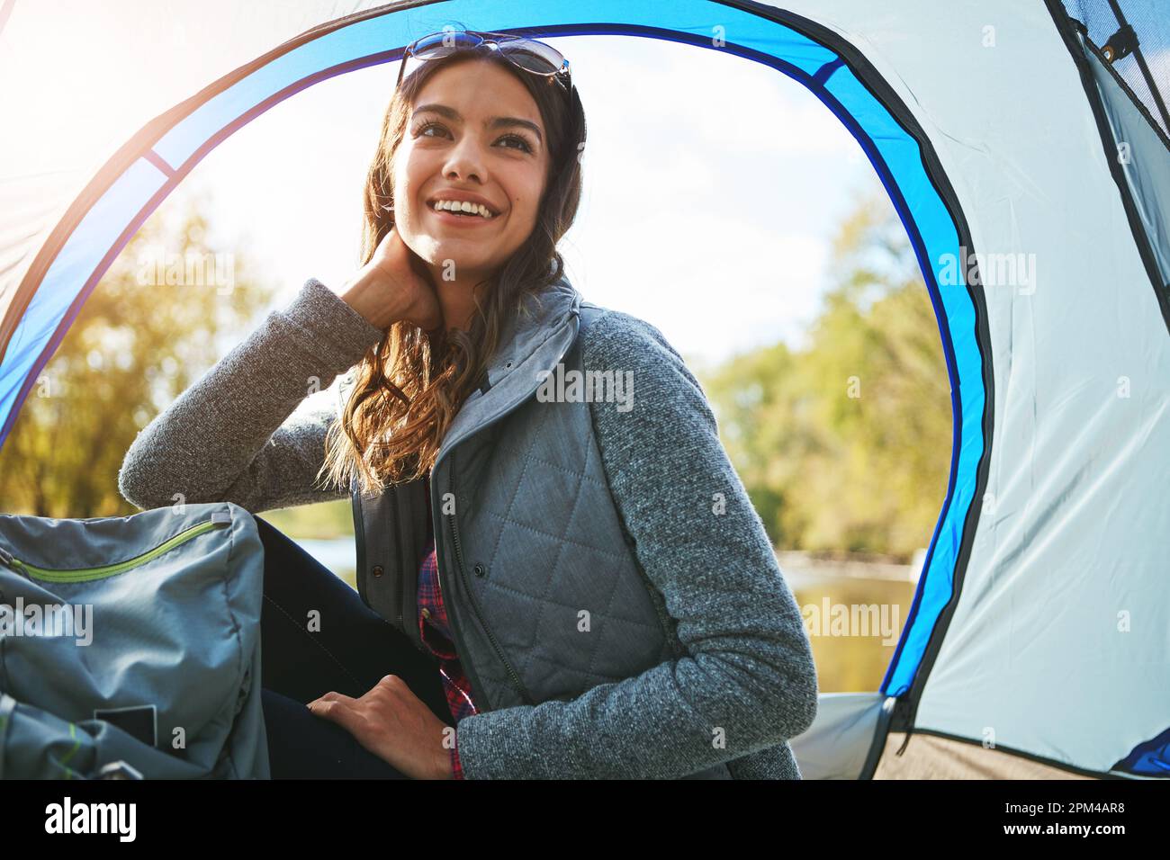 Sie entkommt allem. Eine attraktive junge Frau, die auf ihrem Campingplatz sitzt. Stockfoto
