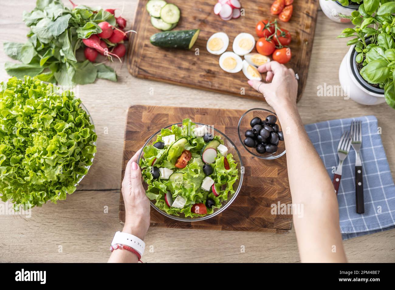 Draufsicht weiblicher Hände bei der Zubereitung eines gesunden Frühlingssalats. Stockfoto