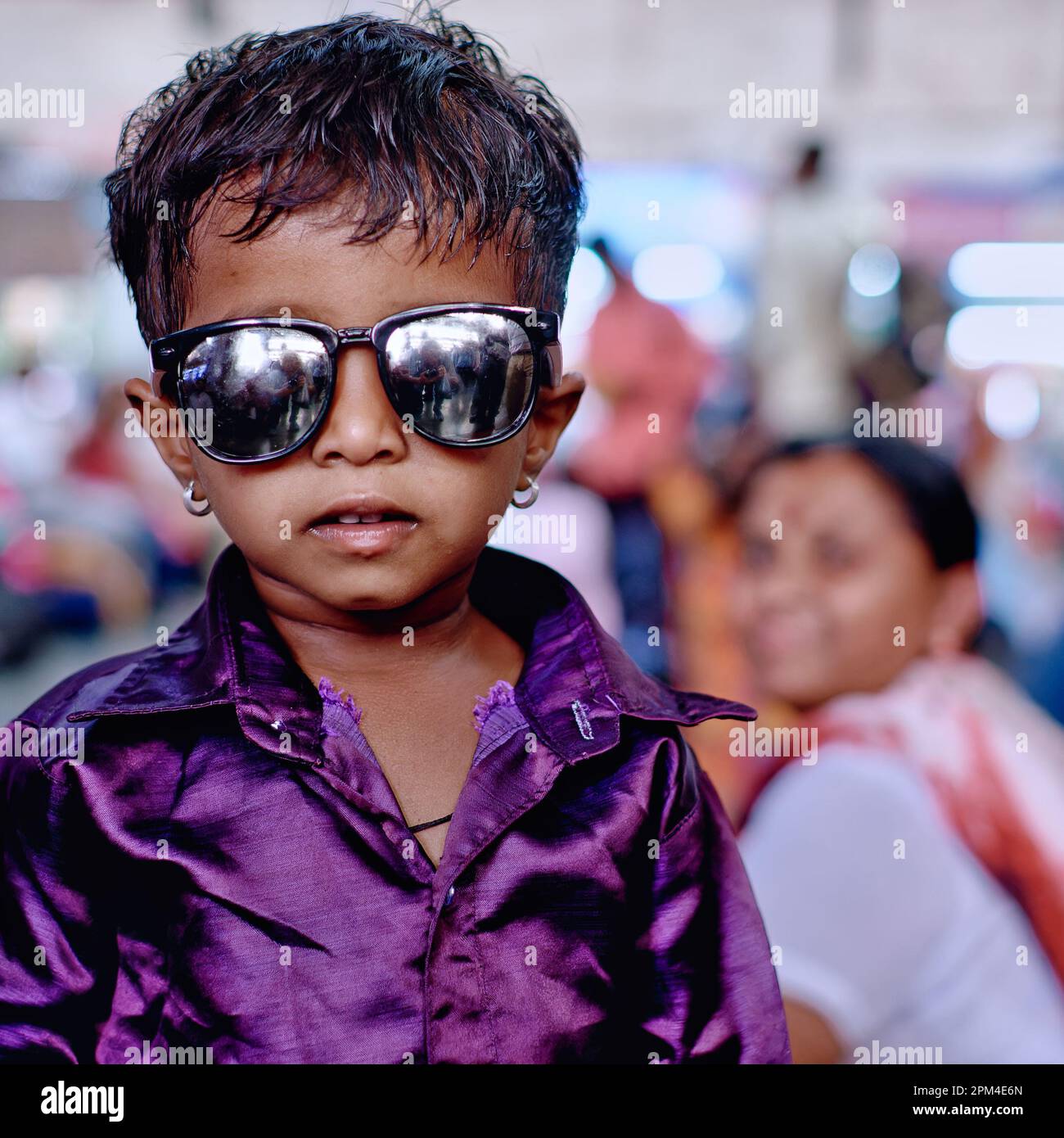 Ein anständig gekleideter indischer Junge im Kindergartenalter, der eine Sonnenbrille und Ohrringe trägt, anscheinend im Stil der Berühmtheiten von Bollywood Stockfoto