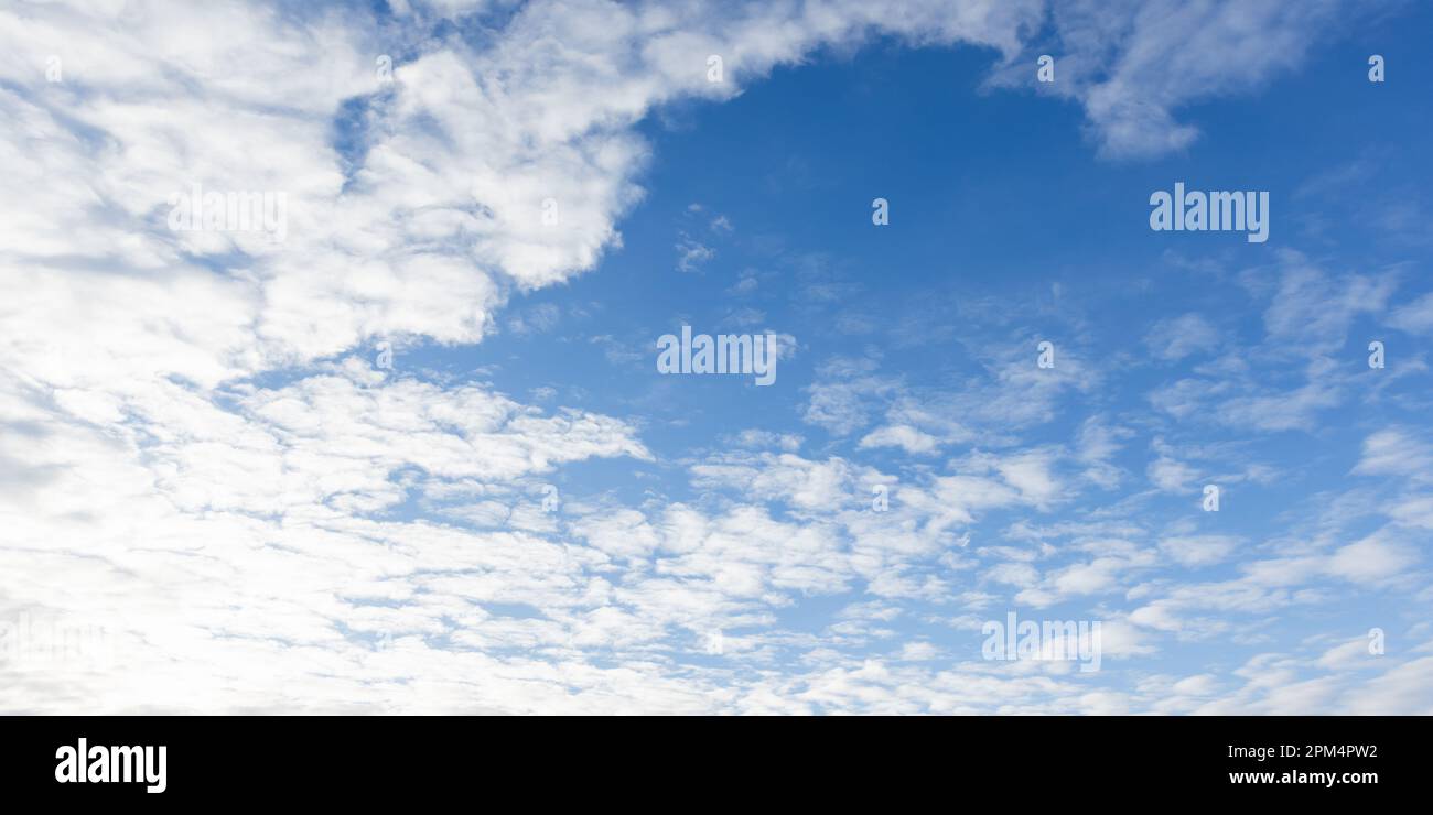 Blaue Himmelsstruktur mit weißen Altocumuluswolken an einem sonnigen Tag, natürliches Hintergrundfoto Stockfoto