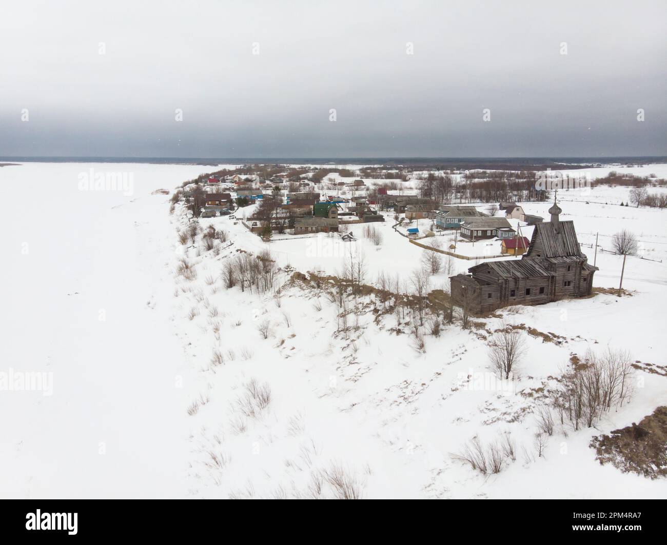 Ein Dorf am Rand einer Klippe. Kirche und Glockenturm am Ufer der nördlichen Dvina. Russland, Region Archangelsk, Dorf Tschukhcherma Stockfoto