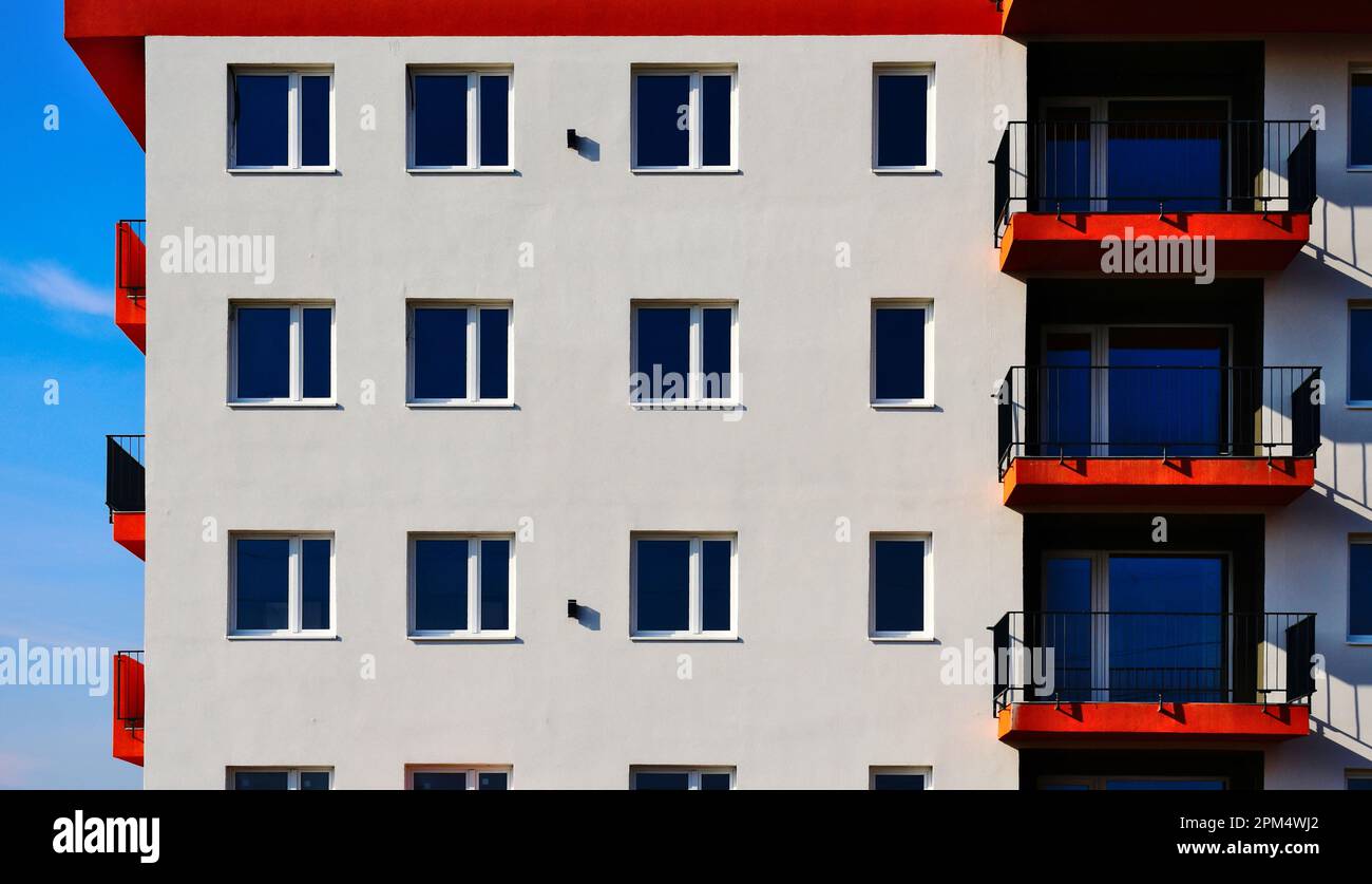 Balkonplatten aus rotem, strukturiertem Stuck. Stahlpavillengeländer. Perspektivische Ansicht. Höhe des Wohngebäudes. Außenansicht aus weißem Stuck. Moderne Architektur Stockfoto