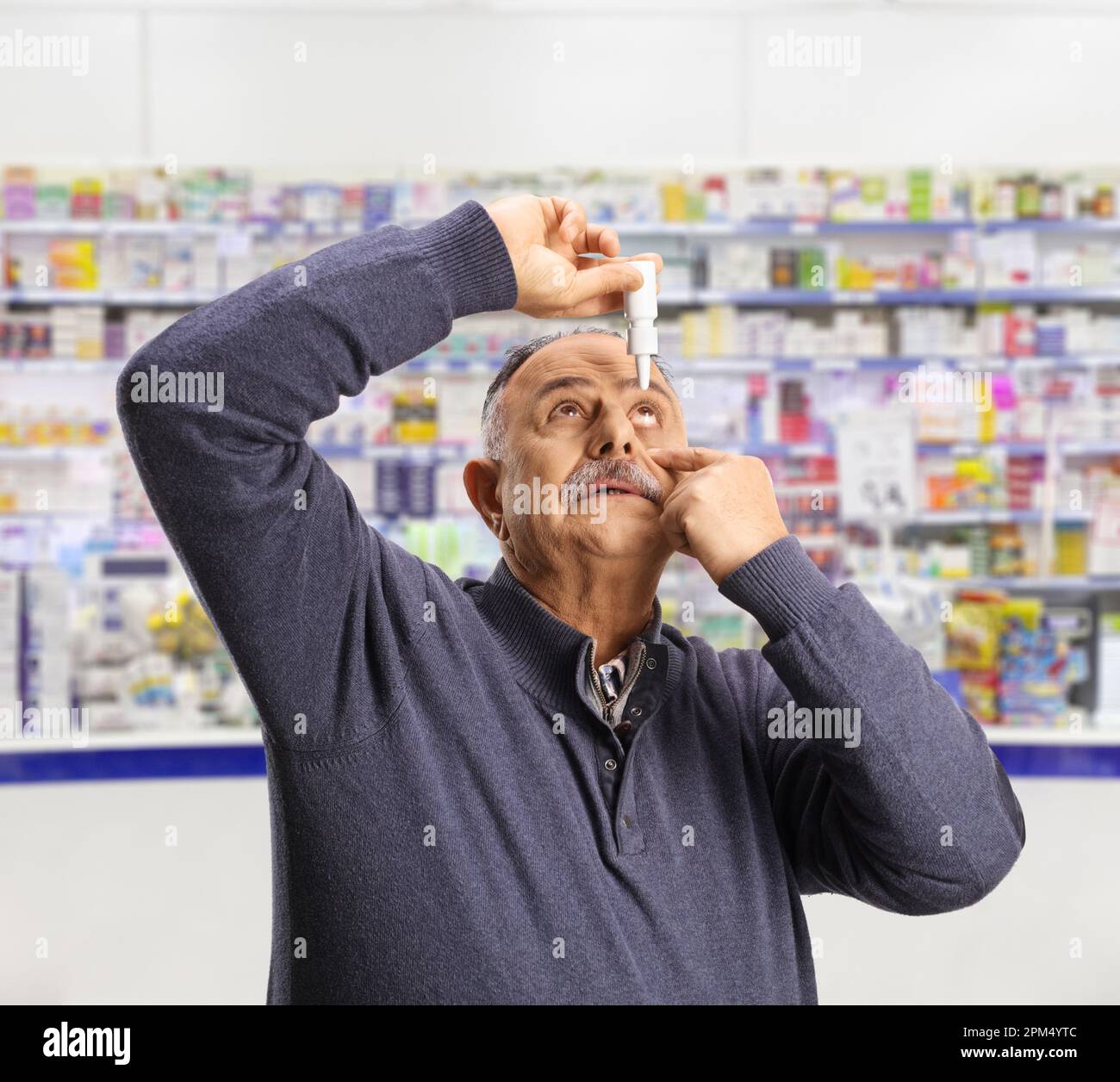 Reifer Mann, der Augentropfen in der Apotheke aufträgt Stockfoto