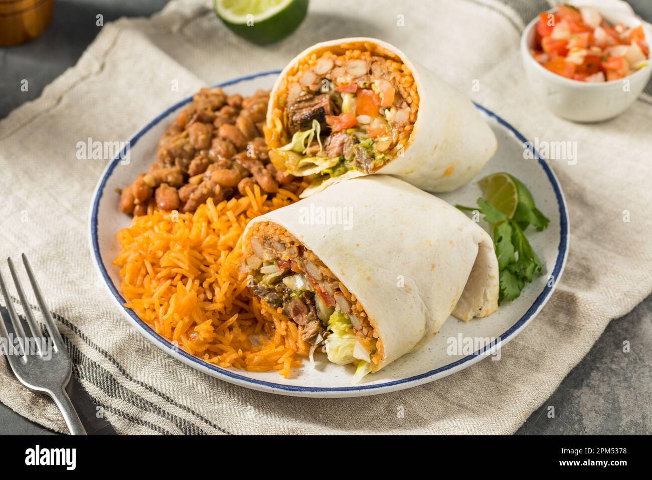 Hausgemachter mexikanischer Cheesy Steak Burrito mit Guacamole und Salsa Stockfoto