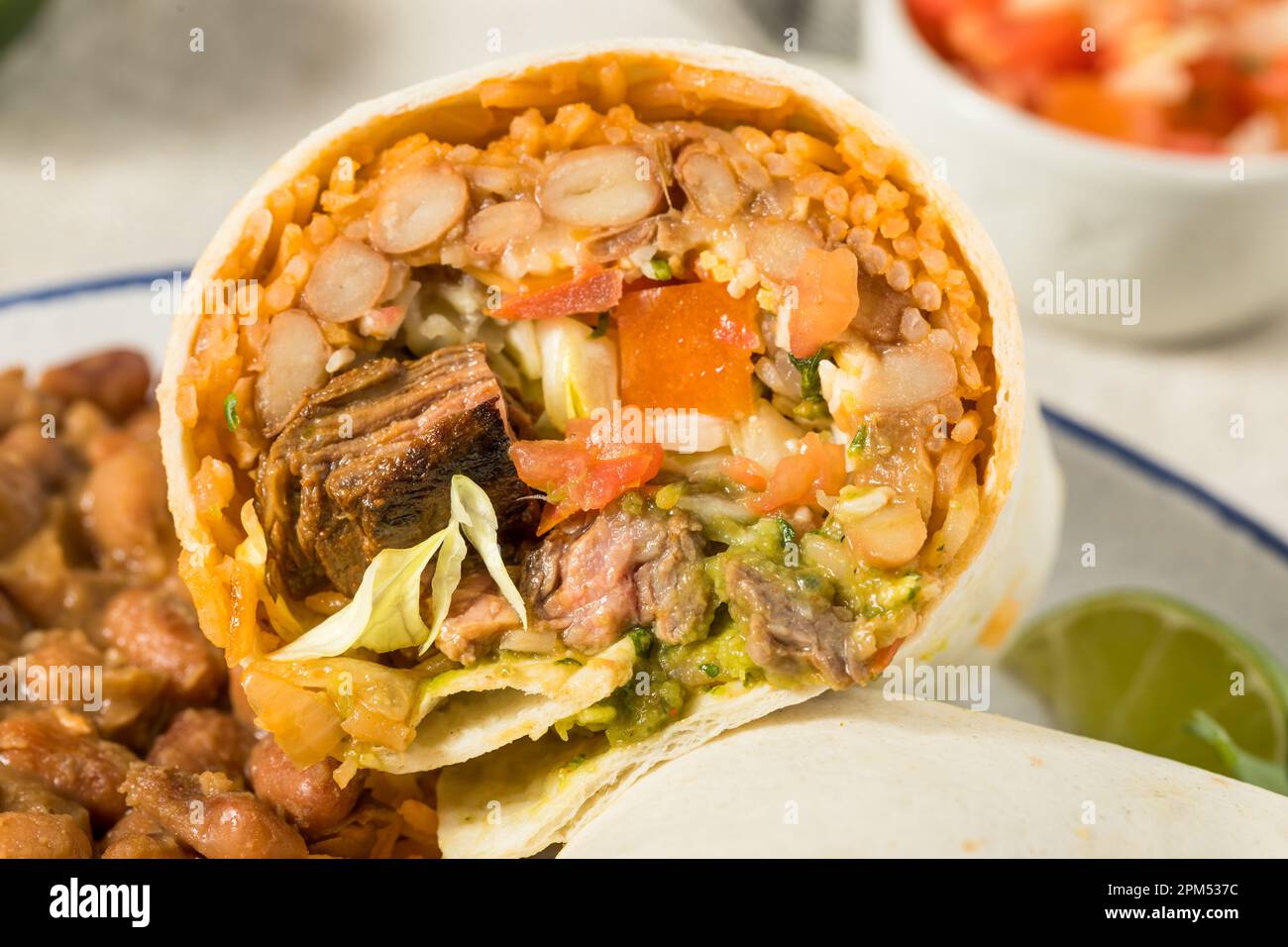 Hausgemachter mexikanischer Cheesy Steak Burrito mit Guacamole und Salsa Stockfoto