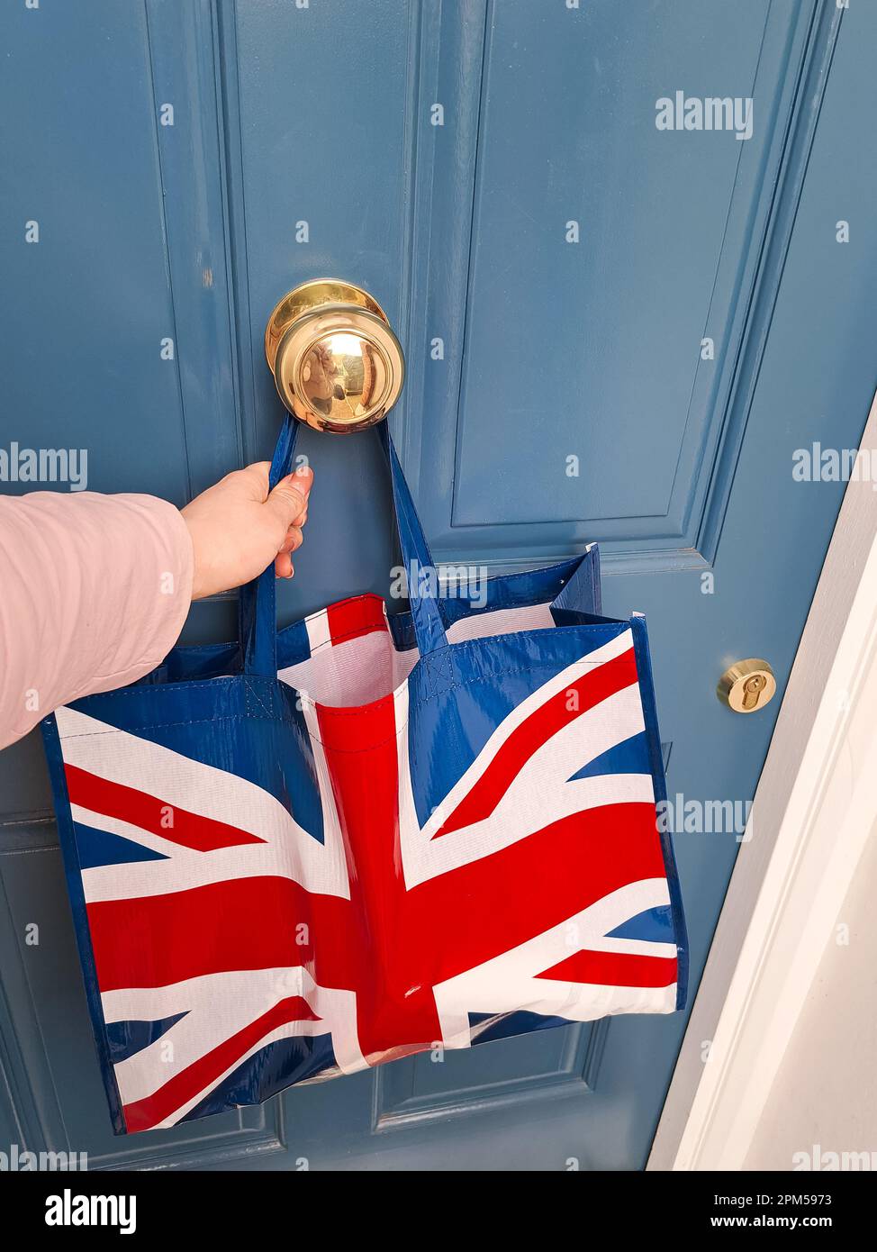 Einkaufstasche mit britischer Flagge in der Nähe der blauen Tür. Hochwertiges Foto Stockfoto