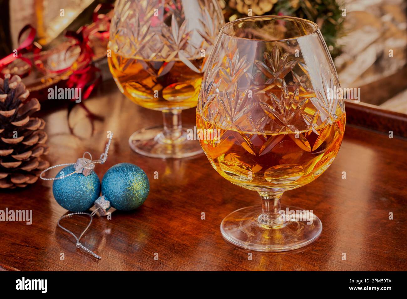 Kristall-Brandy-Gläser voller Brandy mit Weihnachtsdekoration im Hintergrund. Entspannung Stockfoto