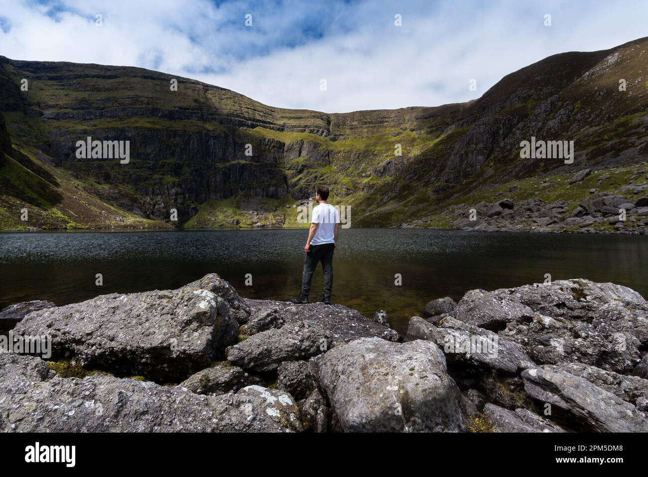 Ein Kletterer steht auf Stein und bewundert den Coumshingaun-See Irland Stockfoto