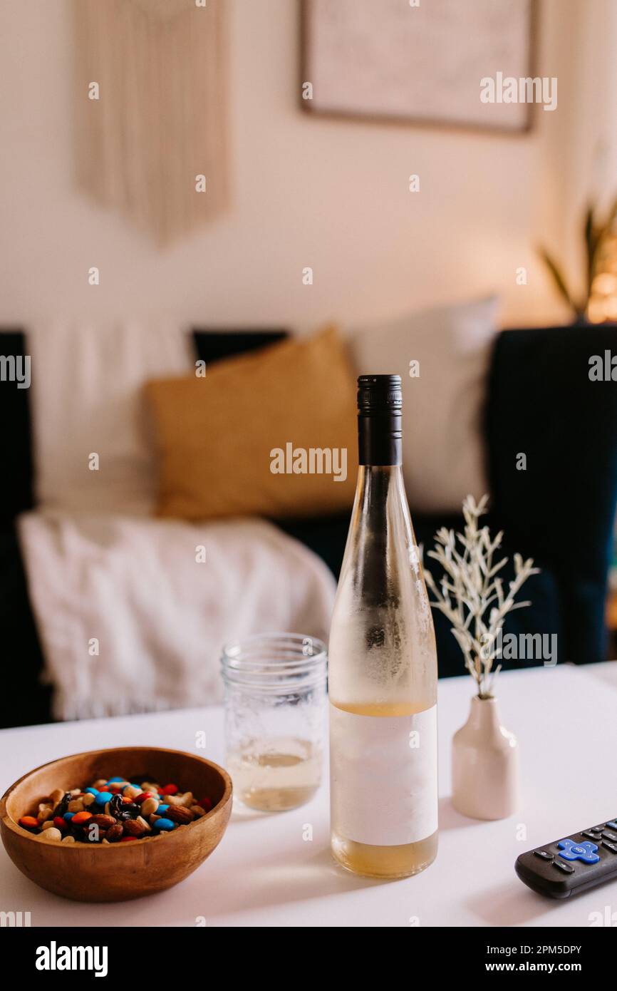 Gemütliches Wohnzimmer mit Snacks, gekühltem Wein und Fernbedienung auf dem Couchtisch Stockfoto Gemütliches Wohnzimmer mit Snacks, gekühltem Wein und Fernbedienung auf dem Couchtisch Stockfoto