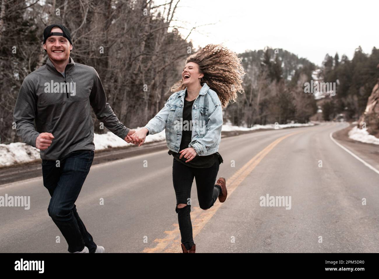 Abenteuerlustiges Paar, das im Winter an der Road in den Colorado Mountains entlang läuft Stockfoto