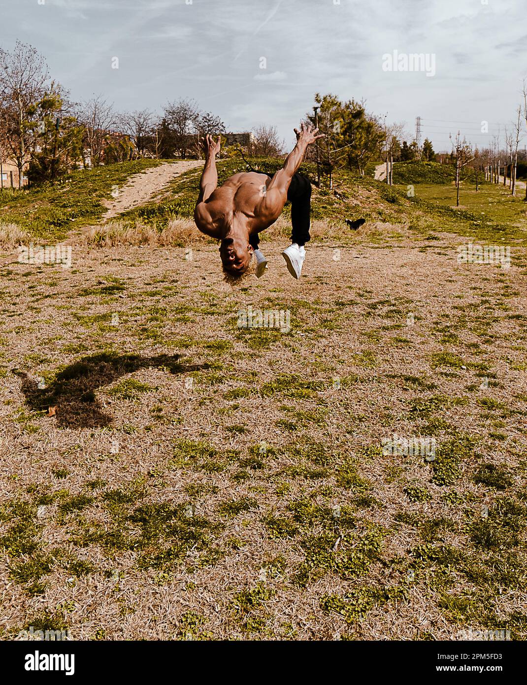 Stock Photo eines Mannes, der auf dem Feld gegen den klaren Himmel einen Salto macht Stockfoto