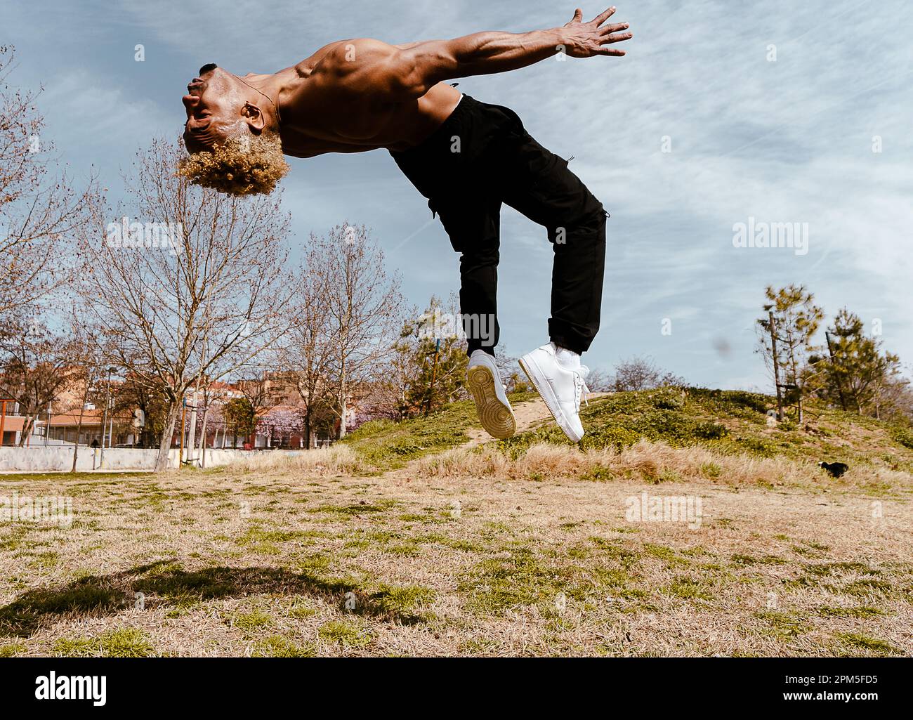 Stock Photo eines Mannes, der auf dem Feld gegen den klaren Himmel einen Salto macht Stockfoto
