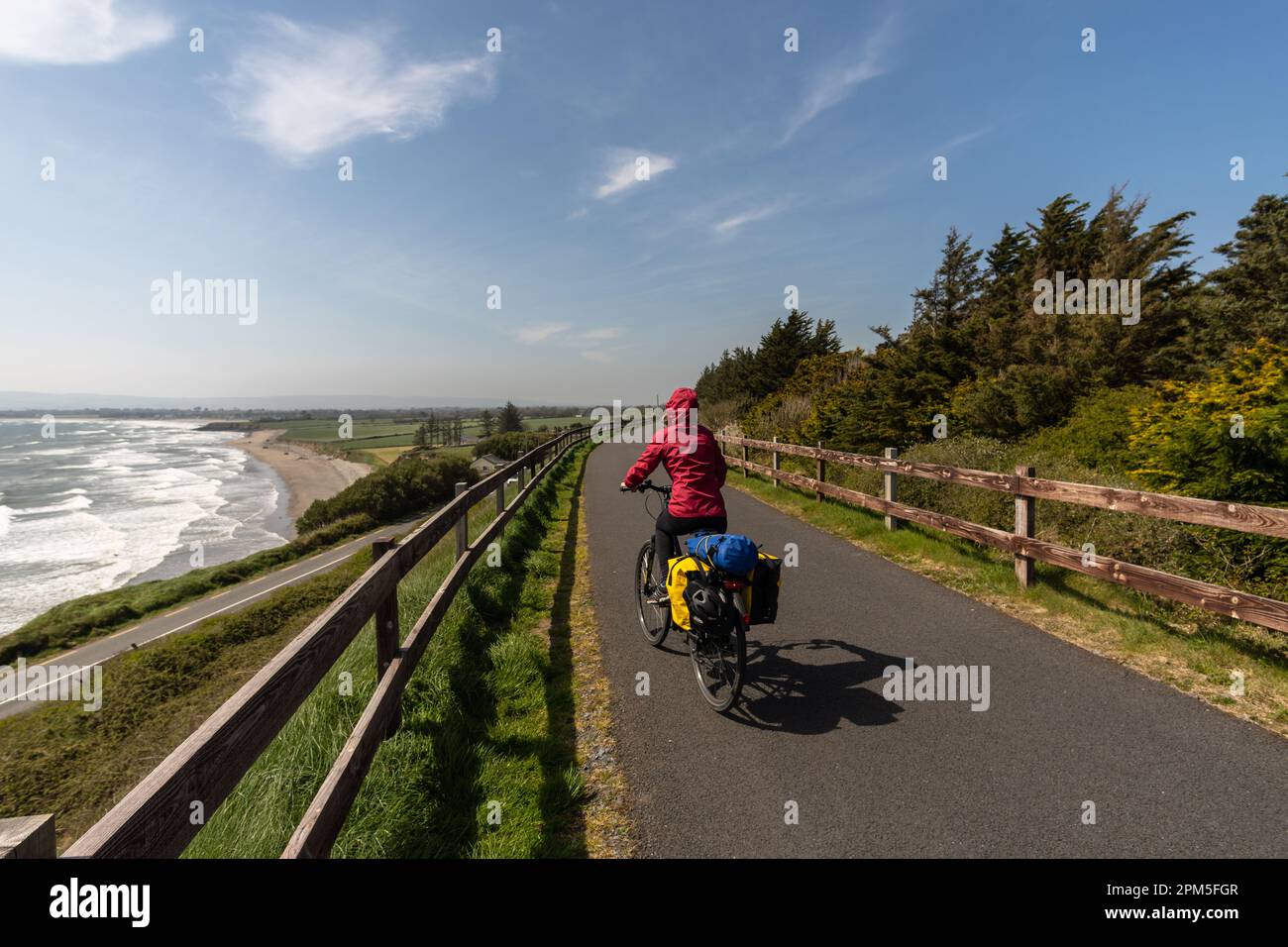Eine Radfahrerin, die auf einer Straße über die Küste fährt Stockfoto
