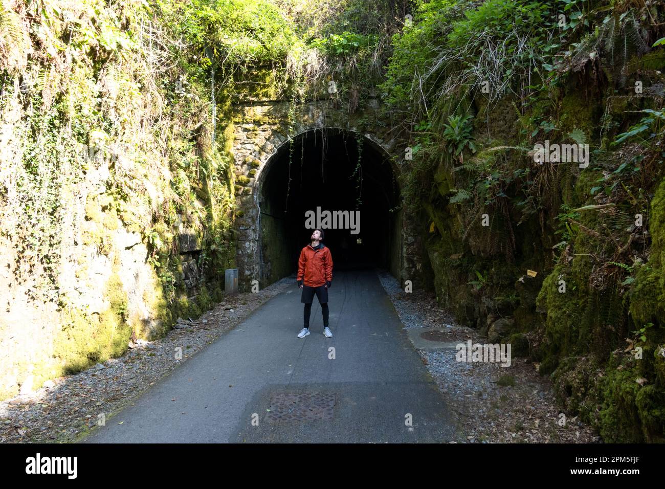 Ein Mann steht vor einem Bergtunnel auf der Straße Stockfoto