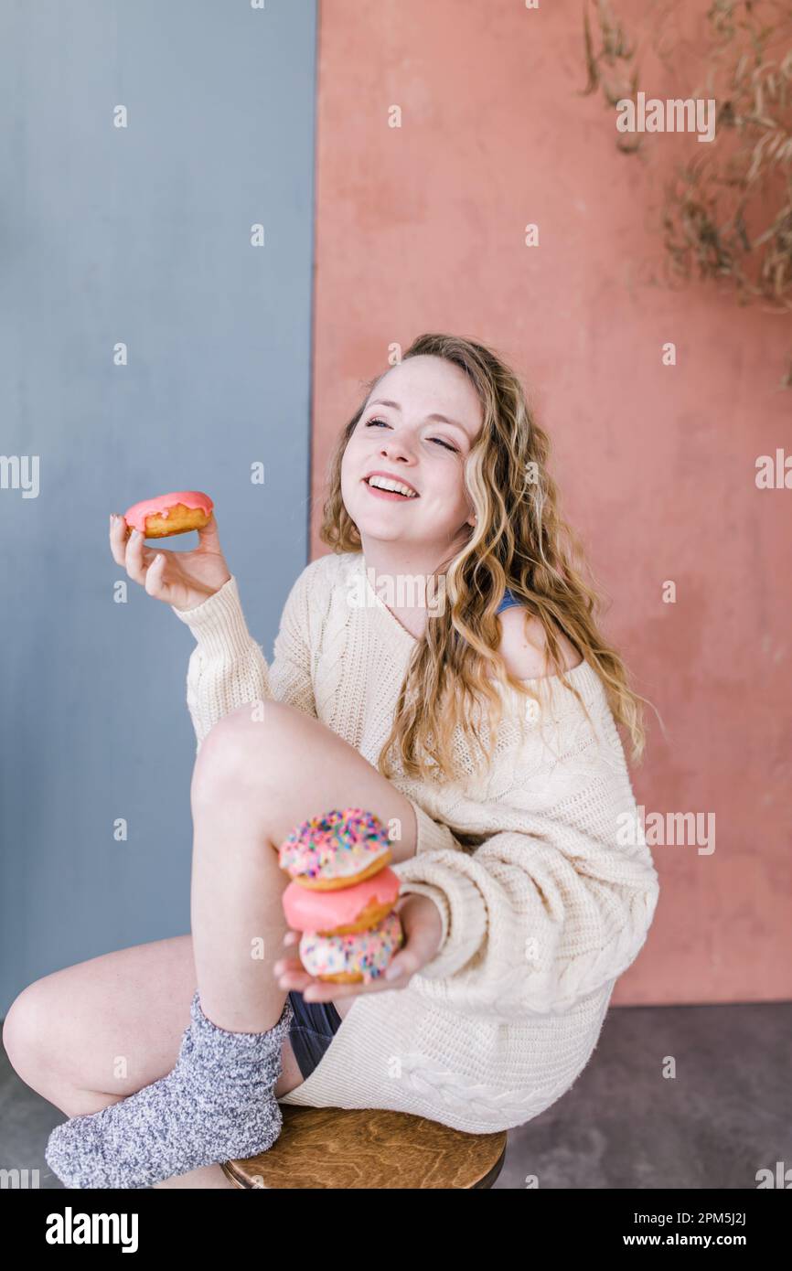 Ein entspannter Erwachsener, der einen Stapel Donuts hält und lacht Stockfoto