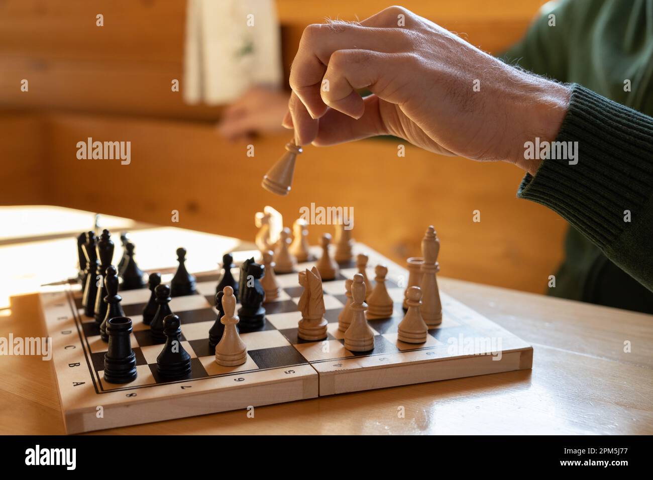 Ein Mann spielt Schach und macht einen Zug mit einem weißen Stück Stockfoto