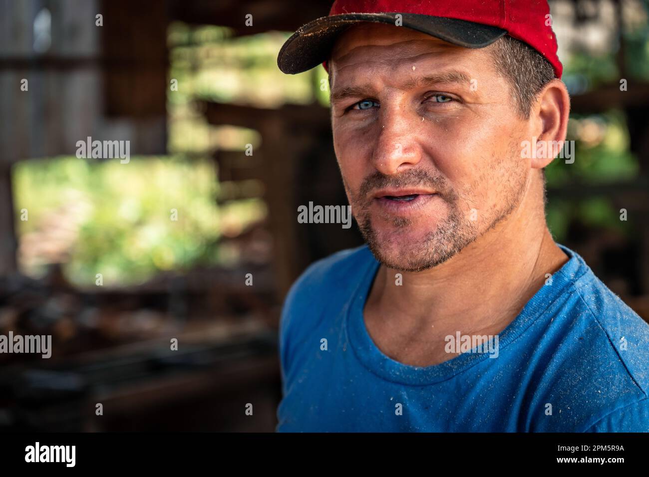 Nahaufnahme eines gutaussehenden männlichen Arbeiters mit rotem Hut, der in die Kamera schaut. Arbeit, Schwerindustrie, Beruf Stockfoto