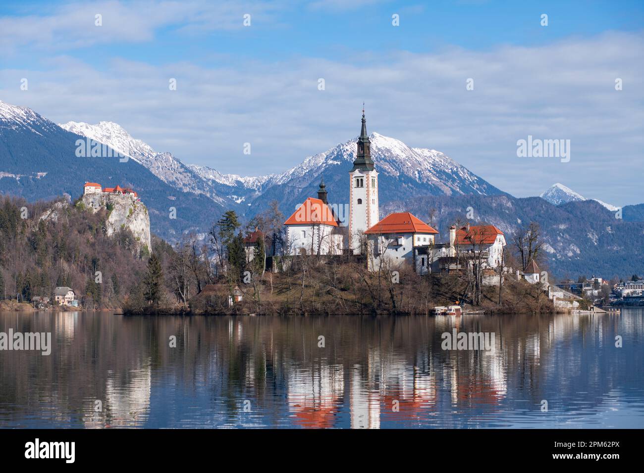 Bleder See: Kirche der Mutter Gottes und Schloss Bled, mit schneebedeckten Bergen im Hintergrund. Slowenien Stockfoto