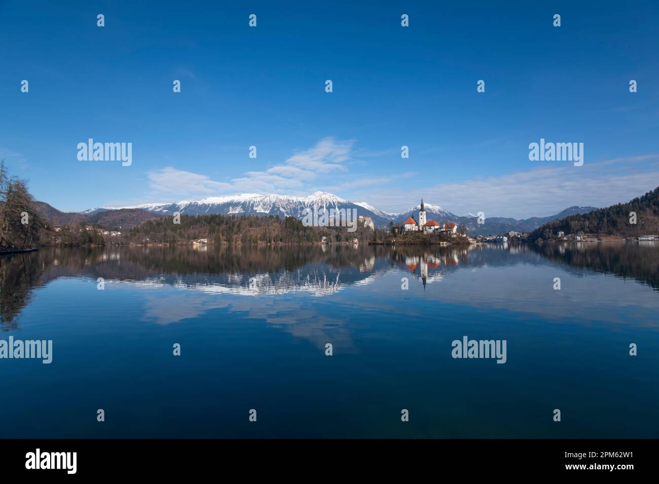 Bleder See: Kirche der Mutter Gottes und Schloss Bled, mit schneebedeckten Bergen im Hintergrund. Slowenien Stockfoto