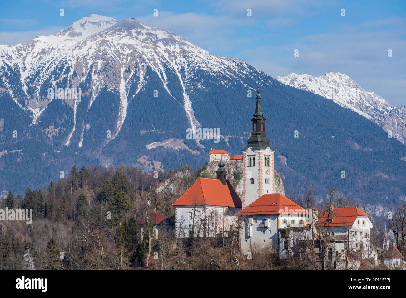 Bleder See: Kirche der Mutter Gottes und Schloss Bled, mit schneebedeckten Bergen im Hintergrund. Slowenien Stockfoto