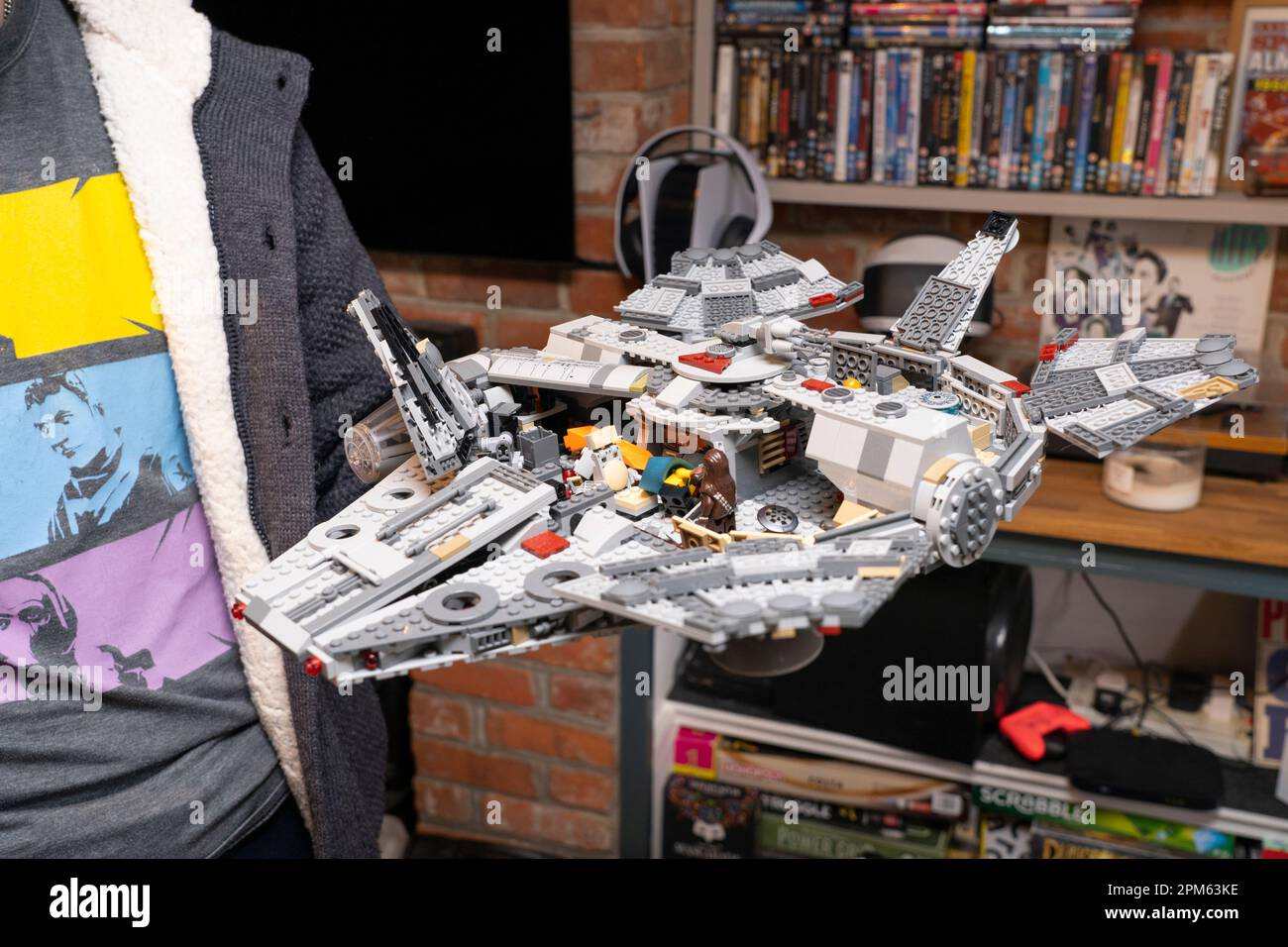 Ein Mann in seinen Dreißigern, der ein Lego-Modell des Star Wars Millenium Falcon zu Hause in Großbritannien in der Hand hat. Ein stillgelegtes Produkt. Thema: Hobbys für Erwachsene, Lego-Fan Stockfoto