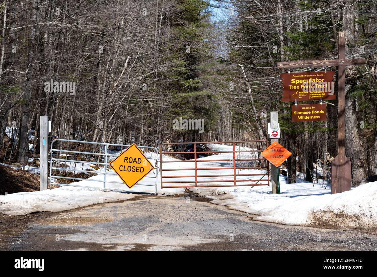 Ein geschlossenes Tor und Schilder weisen darauf hin, dass die Straße im Spätwinter in den Adirondack Mountains, NY, USA wegen Schneefällen gesperrt ist Stockfoto