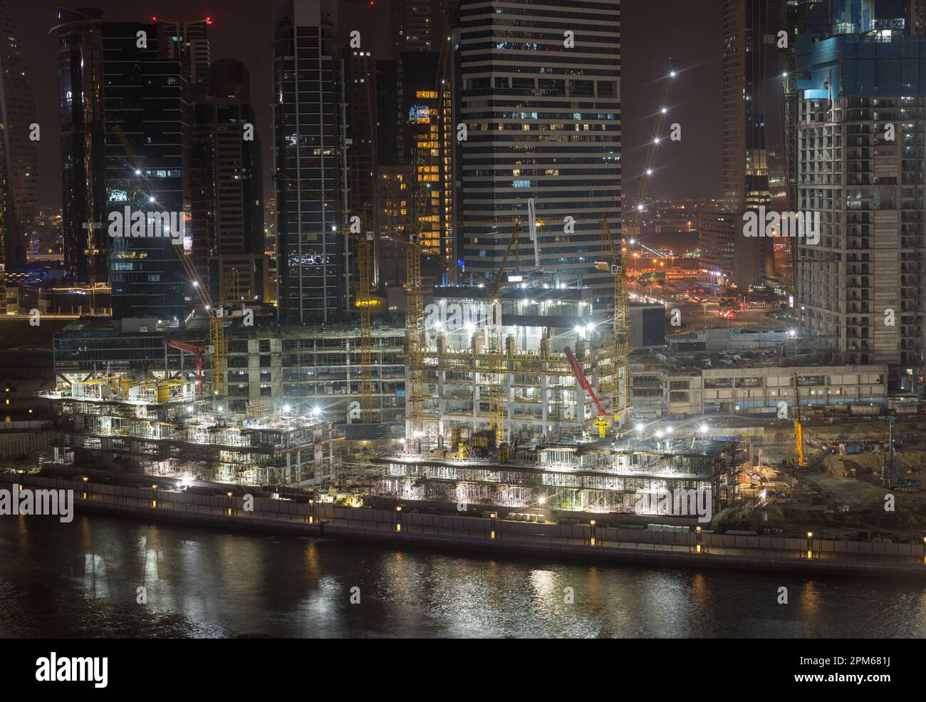 Nächtlicher Bau eines neuen Turms für Apartments entlang des Kanals in der Business Bay von Dubai, Vereinigte Arabische Emirate Stockfoto