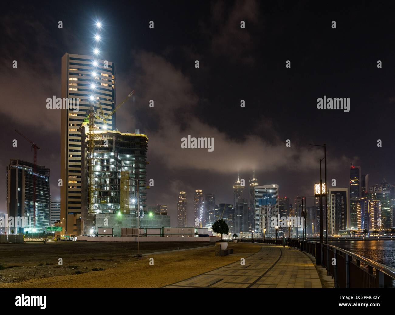 Nächtlicher Bau eines neuen Turms für Apartments entlang des Kanals in der Business Bay von Dubai, Vereinigte Arabische Emirate Stockfoto