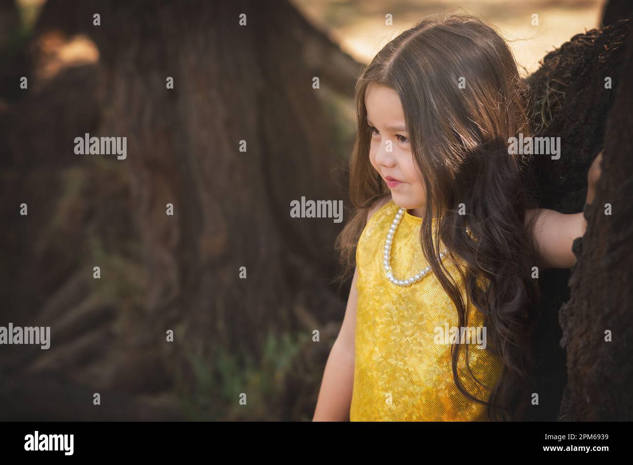 Blondes Mädchen in einer Fotosession, posiert auf einem Baum. Ausdruck des Glücks. Modellmädchen. Kindertag-Thema. Stockfoto