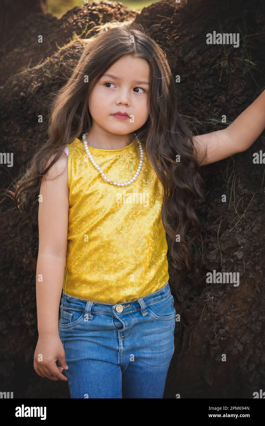 Blondes Mädchen in einer Fotosession, posiert auf einem Baum. Ausdruck des Glücks. Modellmädchen. Kindertag-Thema. Stockfoto