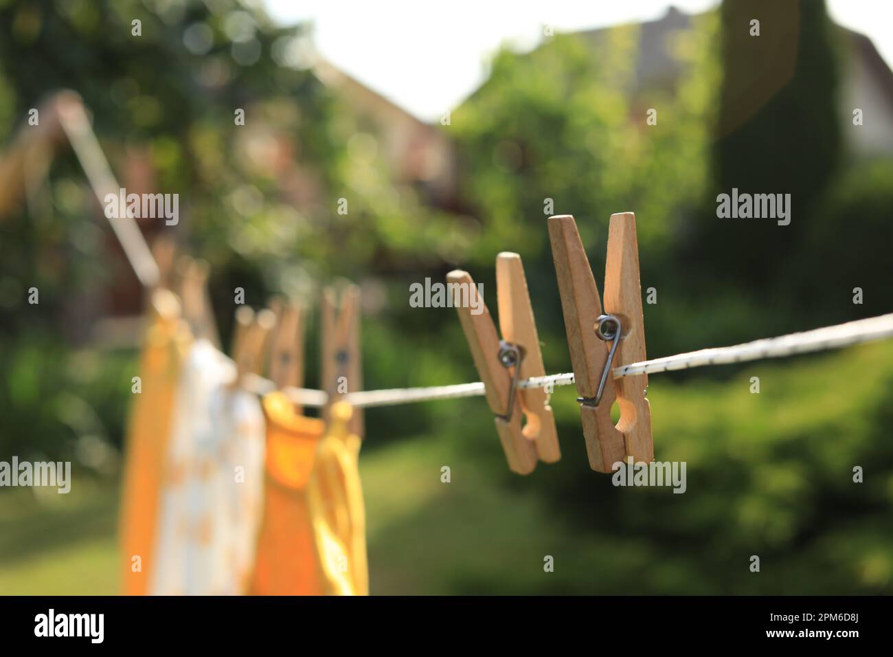 Saubere Kleidung trocknet an sonnigen Tagen im Freien, konzentrieren Sie sich auf die Wäscheleine mit Holzkleidern Stockfoto