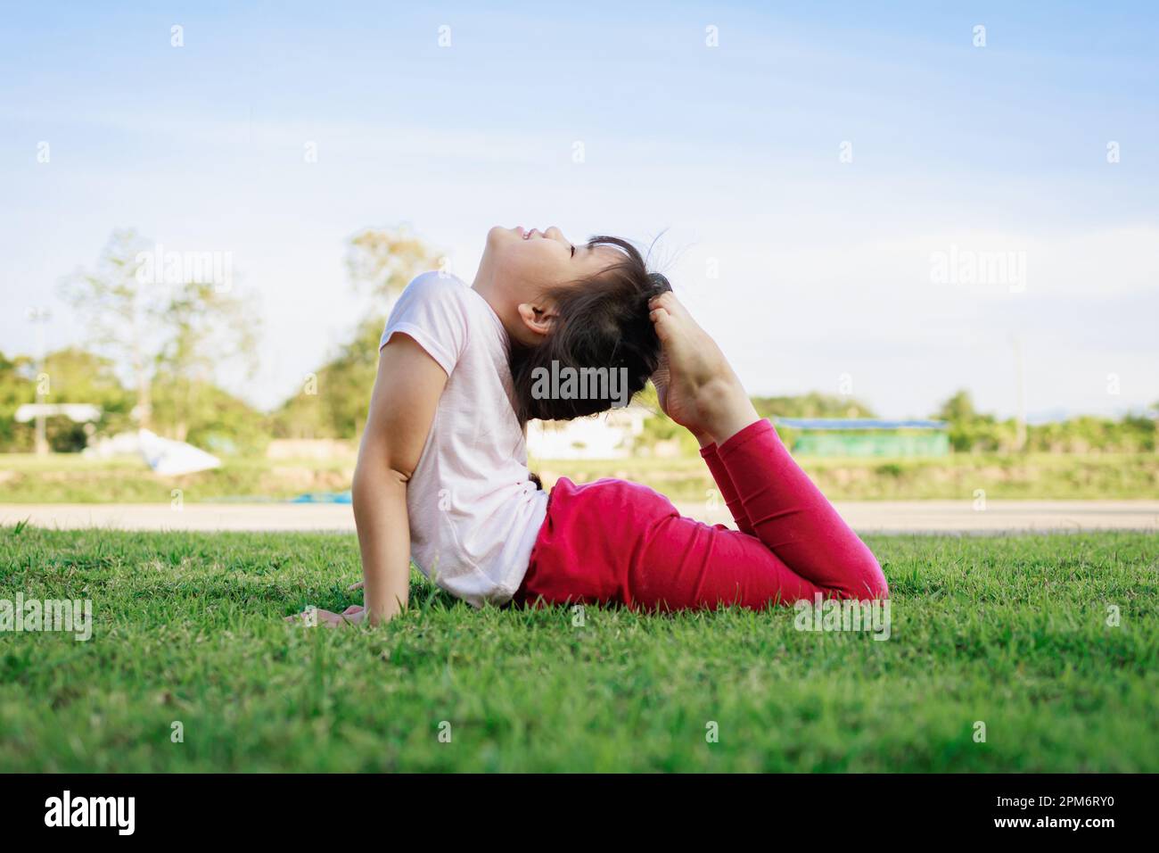 Kindermeditation mit Yoga-Pose auf grünem Grasfeld. Aktivitäten im Freien für Kinder, Yoga-Übungen, Kinder können lernen, wie man trainiert. Stockfoto