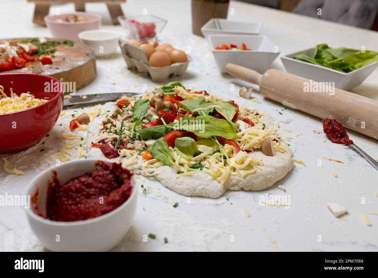 Nahaufnahme von Lebensmittelzutaten und Pizza auf der Arbeitsfläche in der Küche Stockfoto